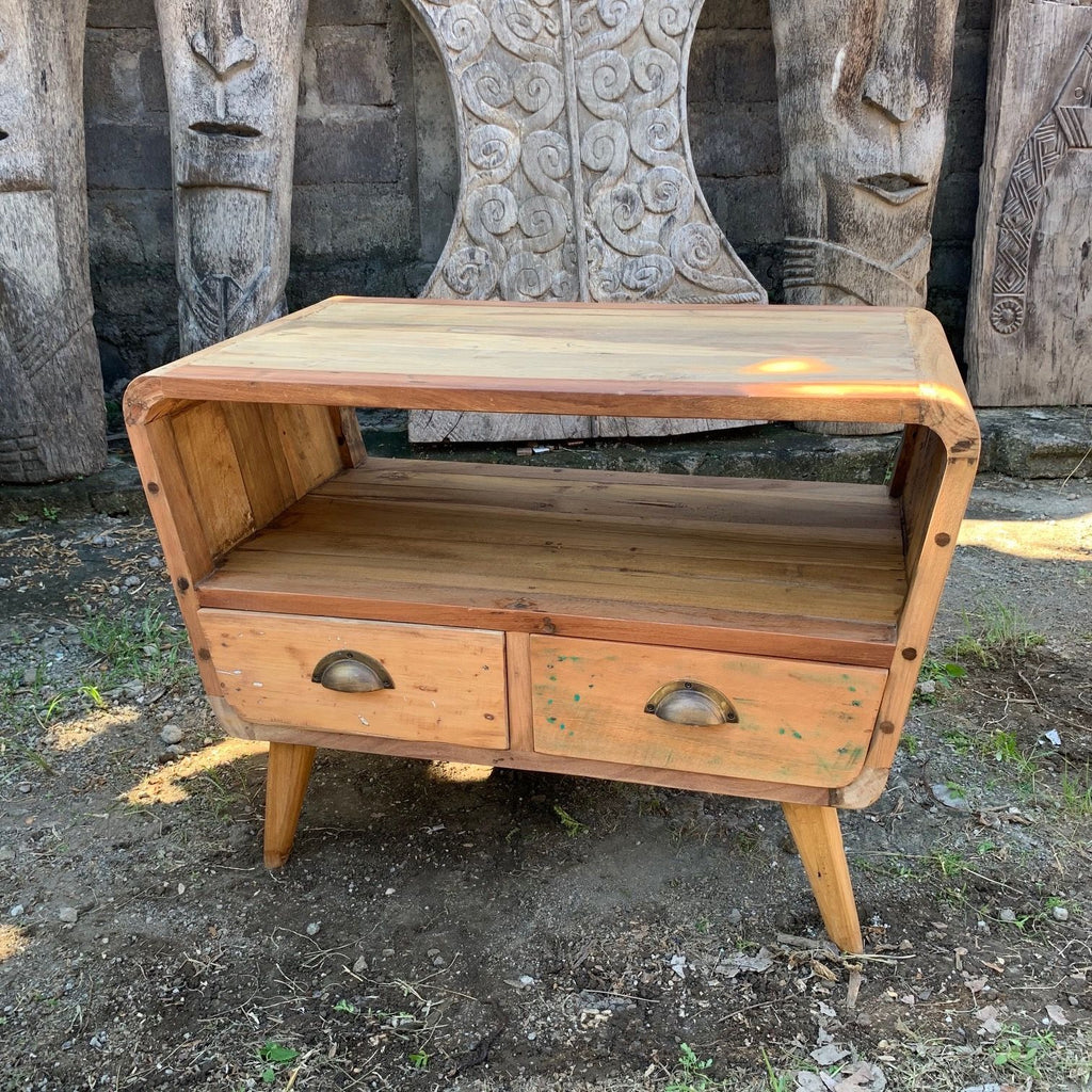 Wooden side table with two drawers in front of stone carvings