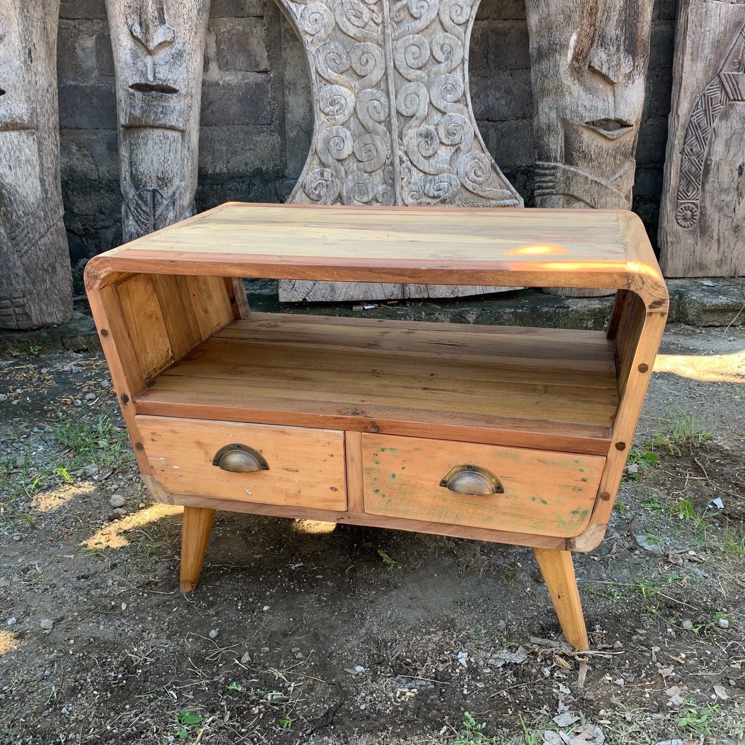 Wooden side table with two drawers in front of stone carvings