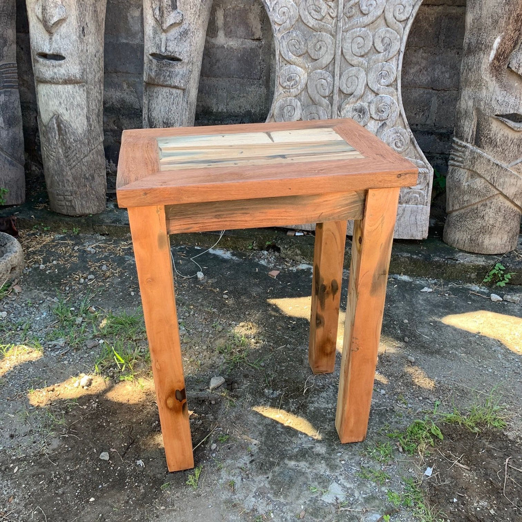 Wooden stool in front of stone sculptures on a dirt ground