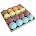 Festive bath bomb assortment in a cardboard tray, pastel purple, blue, green, and tan round balls