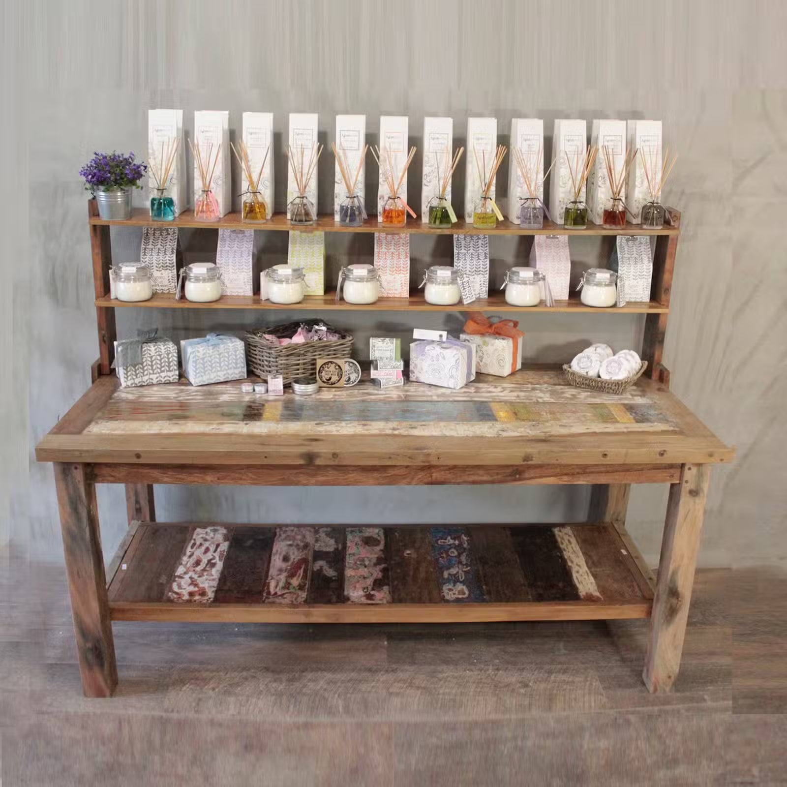 Wooden display table with various products against a gray wall