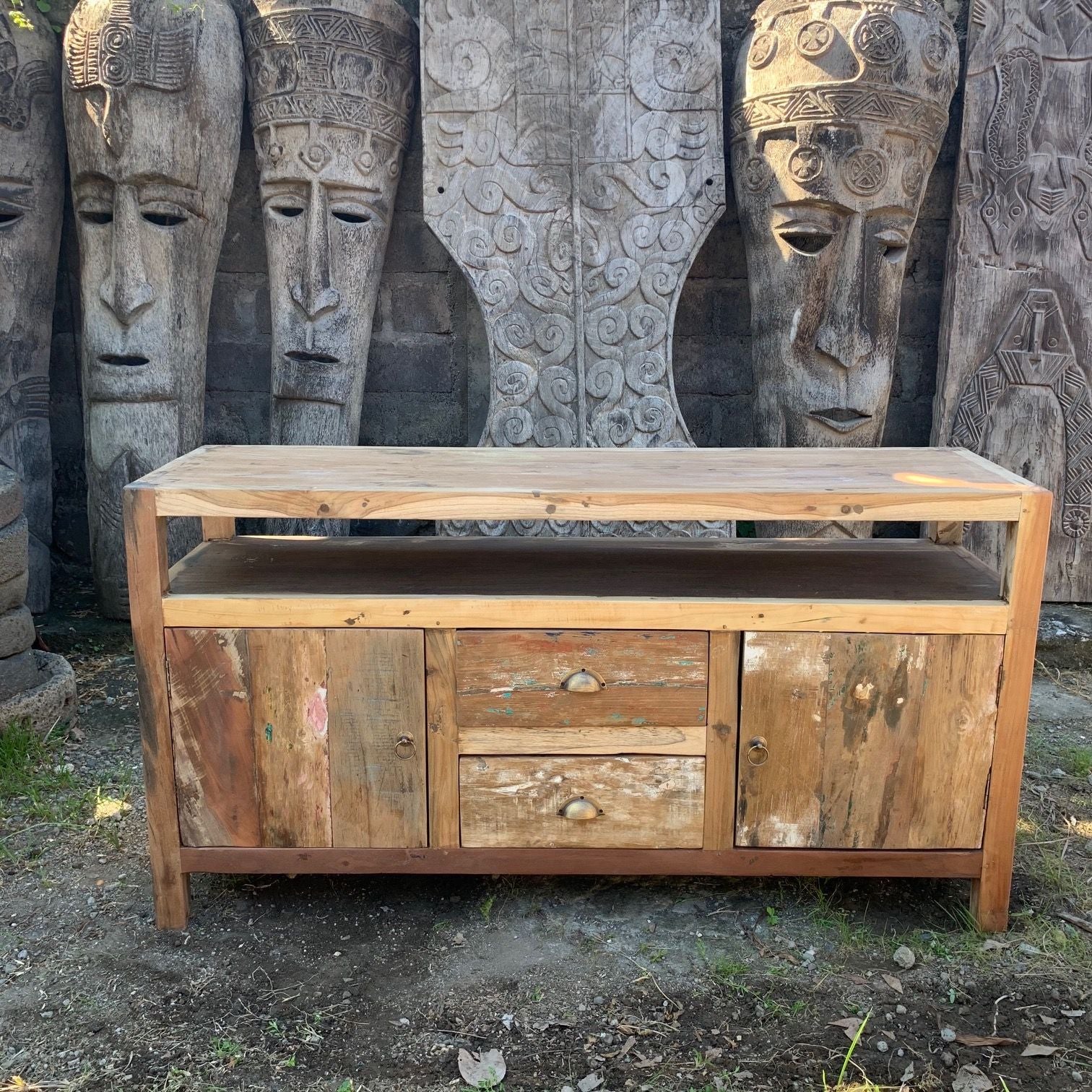 Wooden sideboard with rustic design in front of stone carvings