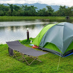 Portable camping cot, grey fabric bed with steel legs, beside green camping tent