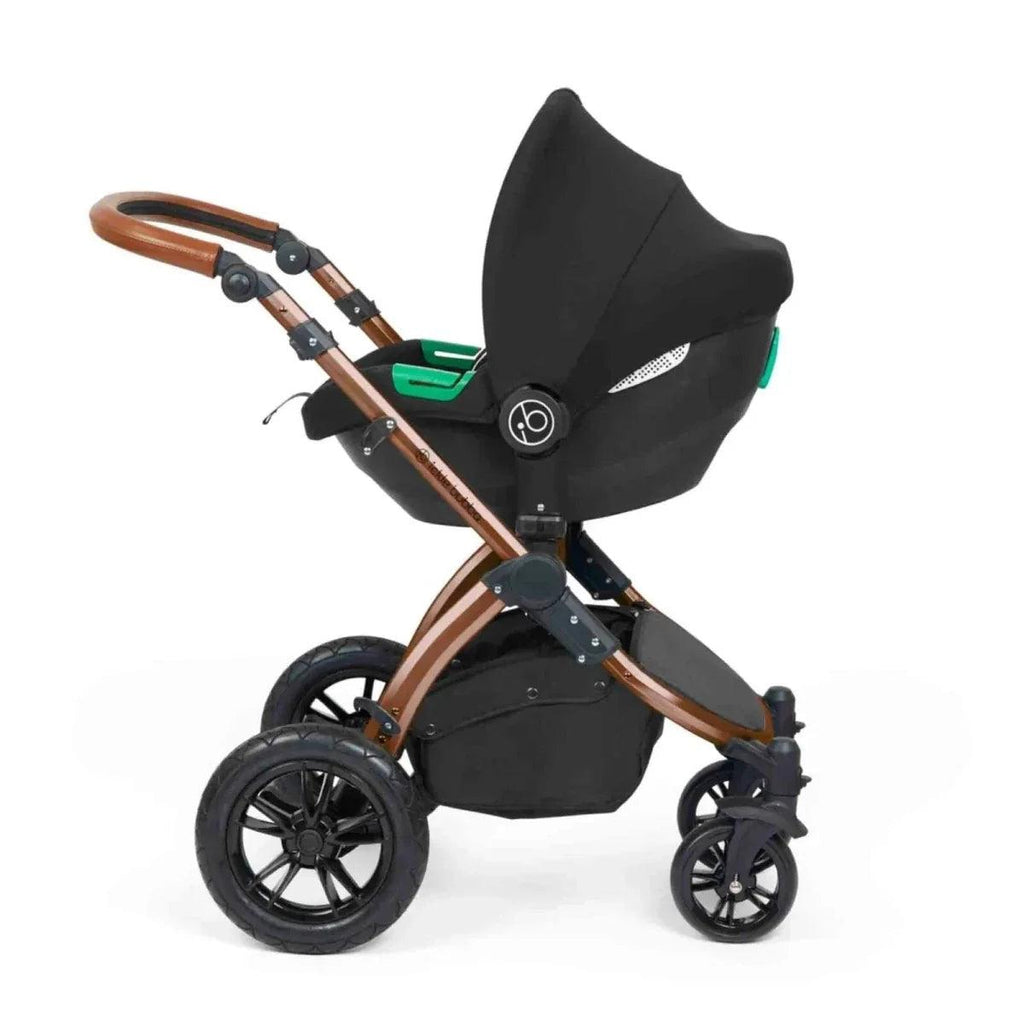 Black pushchair with green release indicators and bronze handlebar, angled seat view