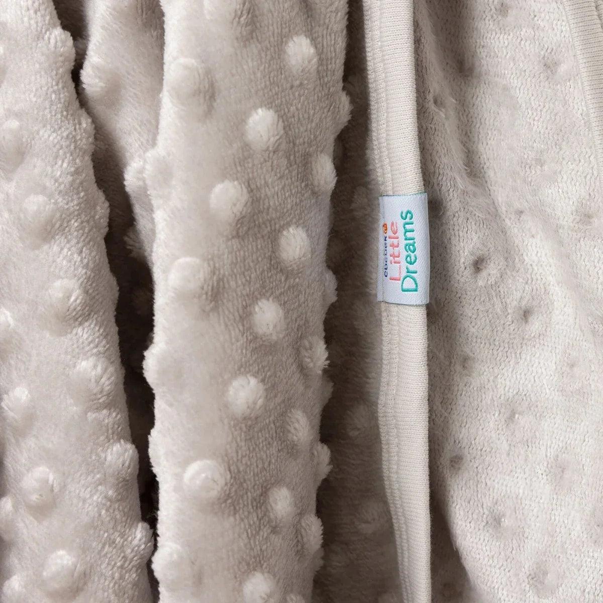 Beige fleece baby blanket with raised dots and 'Dreams' label at the edge