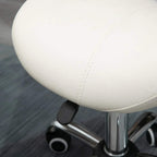 Cream padded saddle stool seat detail with stitched upholstery and rolling caster base