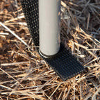 Windbreak pole sleeve and base shown on sandy ground, with black fabric trim