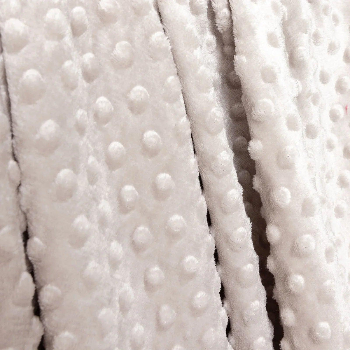 Close-up of beige fleece baby blanket fabric with raised dot texture