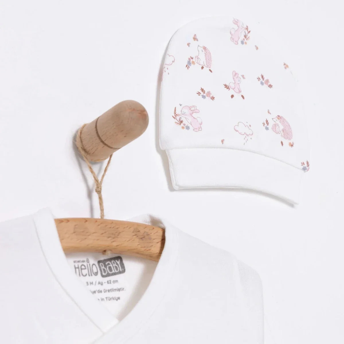Ecru baby hat with pink bunny pattern and neckline of matching long-sleeve top
