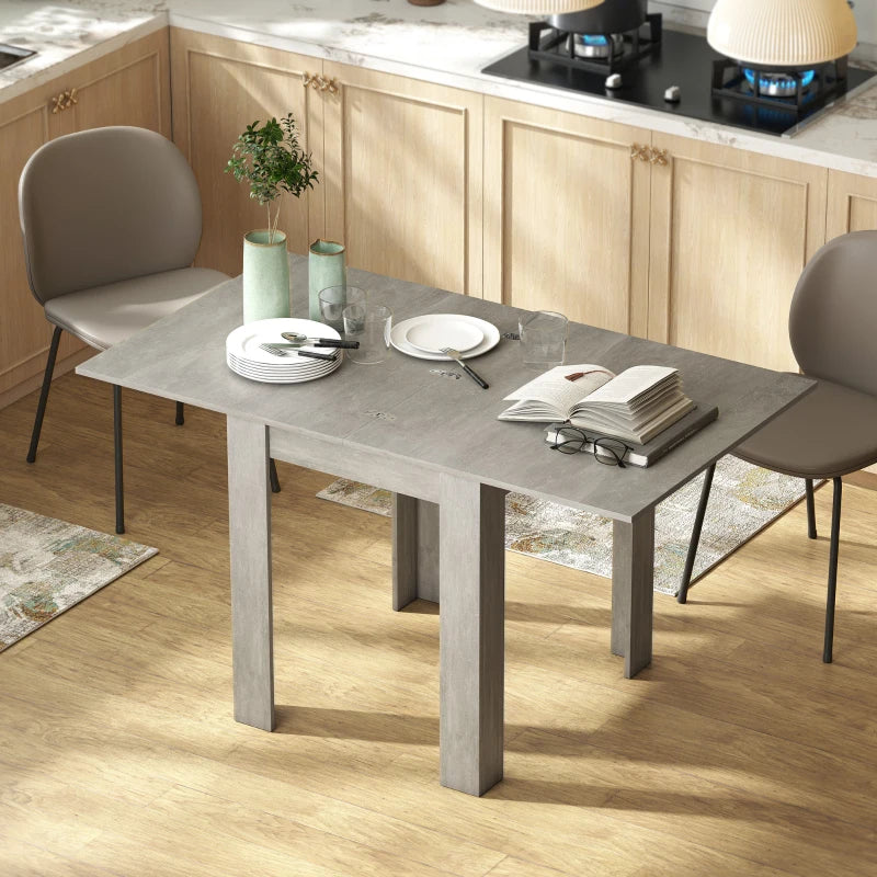 Grey dining table with rectangular drop-leaf design and four legs, seated setup.