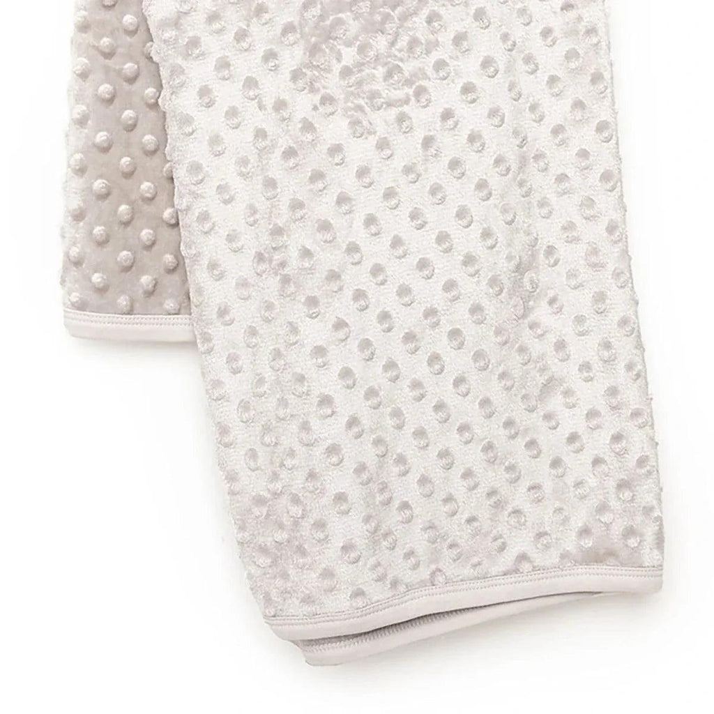 Beige fleece baby blanket with raised dot pattern and stitched border hem