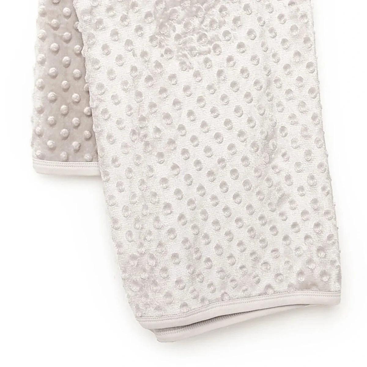 Beige fleece baby blanket with raised dot pattern and stitched border hem