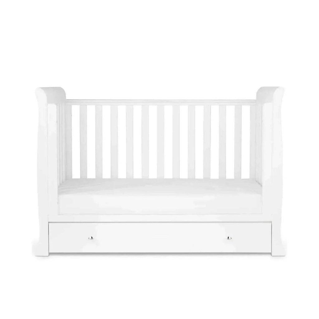 White mini crib with slatted sides, open mattress space, and front drawer
