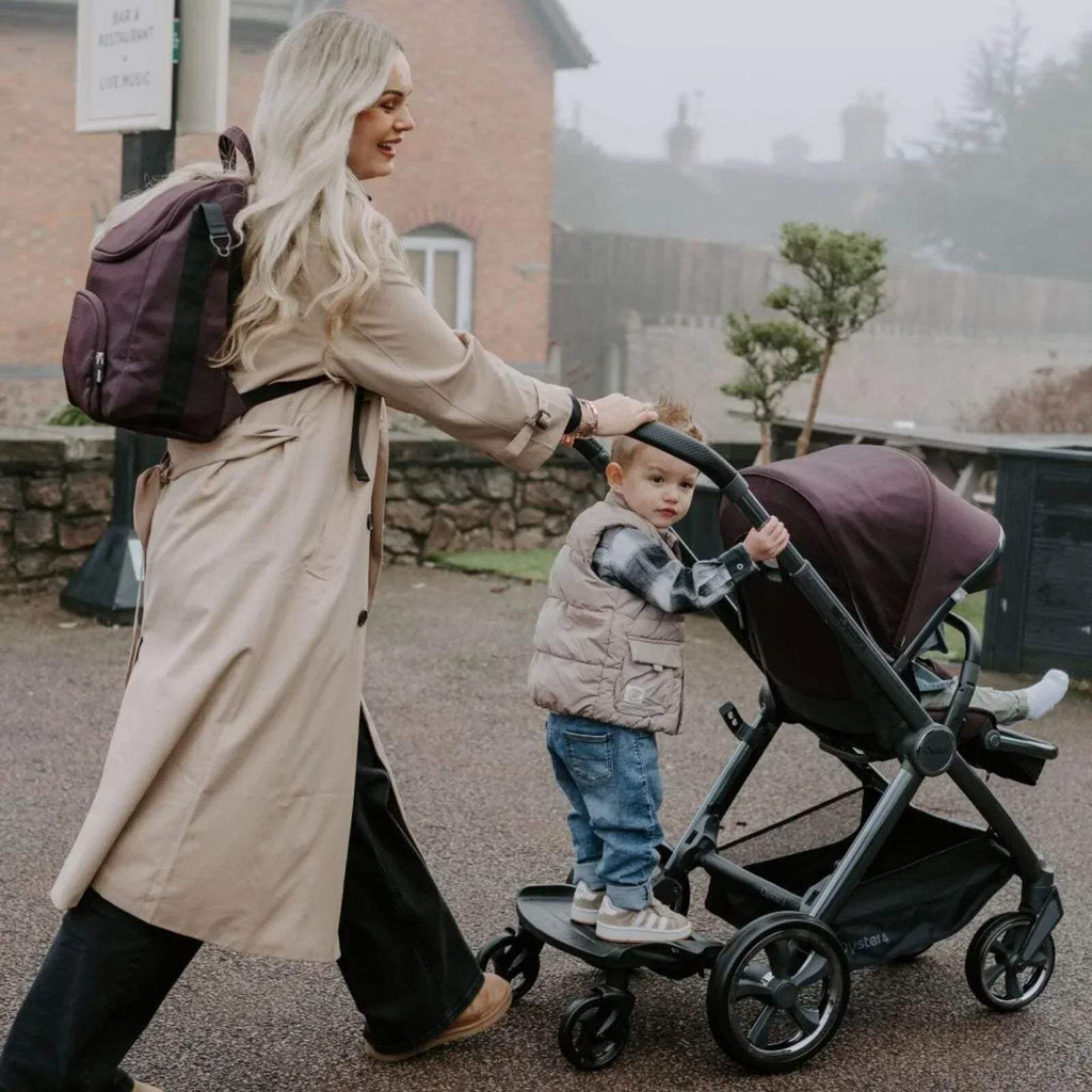 Buttermilk stroller being pushed with padded seat and canopy on black frame and wheels