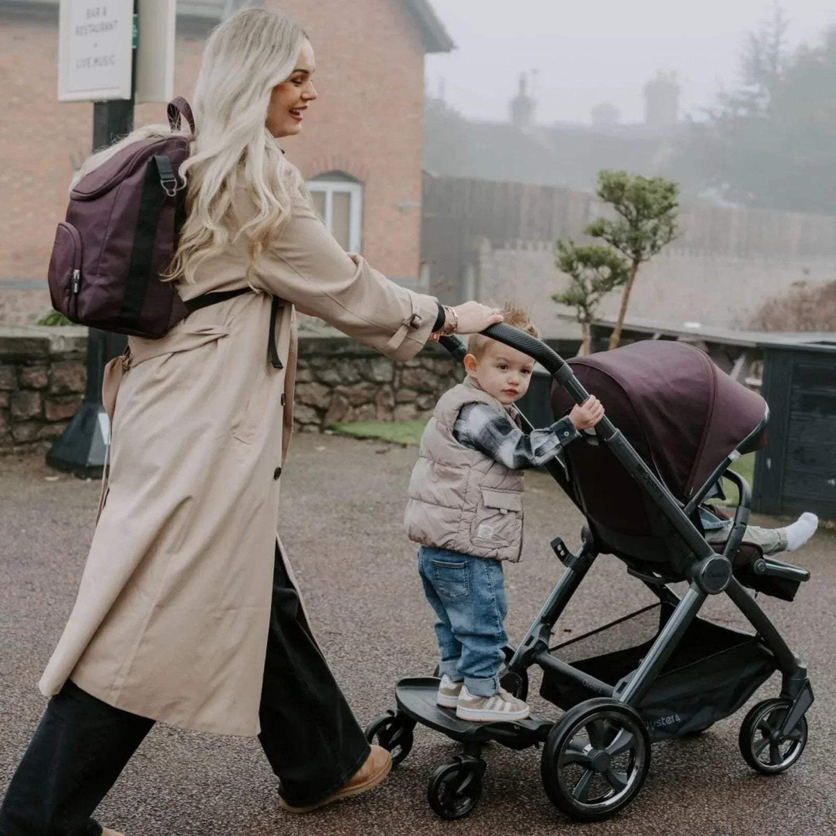 Buttermilk stroller being pushed with padded seat and canopy on black frame and wheels