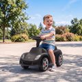 Matte black ride-on push car with steering wheel and front headlights, side view
