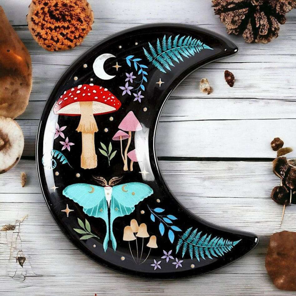 Decorative plate shaped like a crescent moon with fairy tale design on a wooden surface.