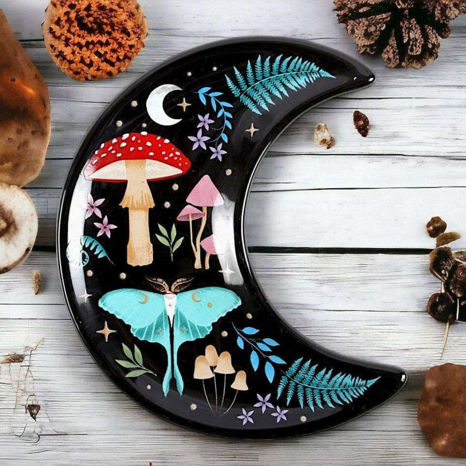 Decorative plate shaped like a crescent moon with fairy tale design on a wooden surface.