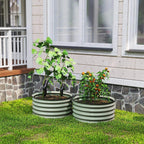 Two green ribbed metal planter boxes with leafy plants on grass