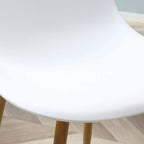 White curved seat of a dining chair with light wood leg base