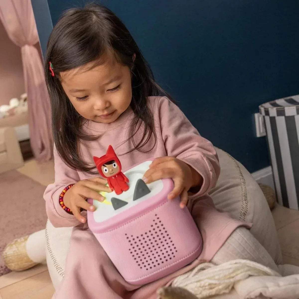 Child holding pink Toniebox 2 audio player with red Creative Tonie character