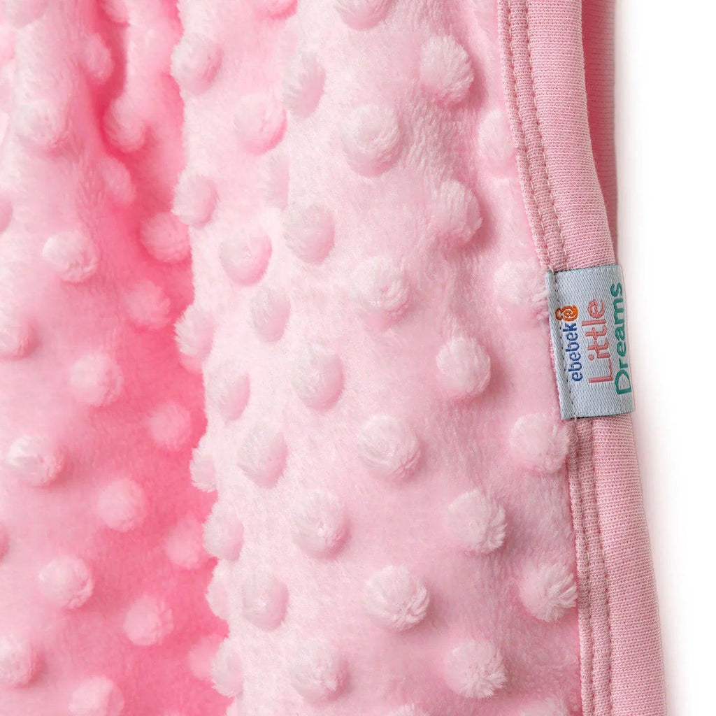 Pink raised-dot fleece baby blanket with stitched edge and fabric label patch.