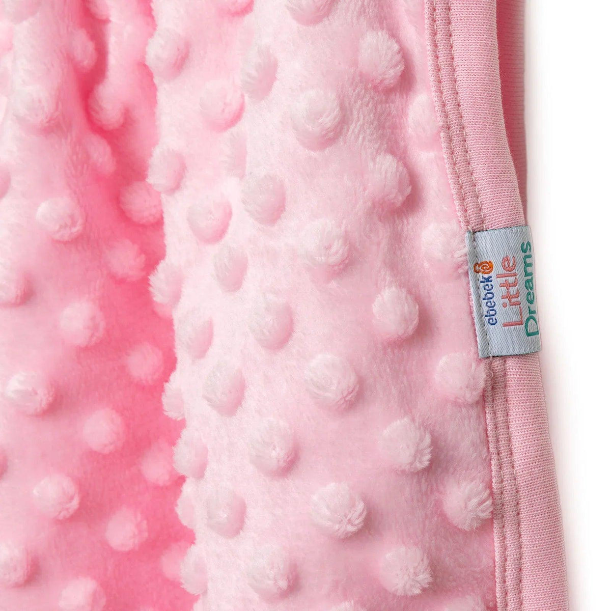 Pink raised-dot fleece baby blanket with stitched edge and fabric label patch.