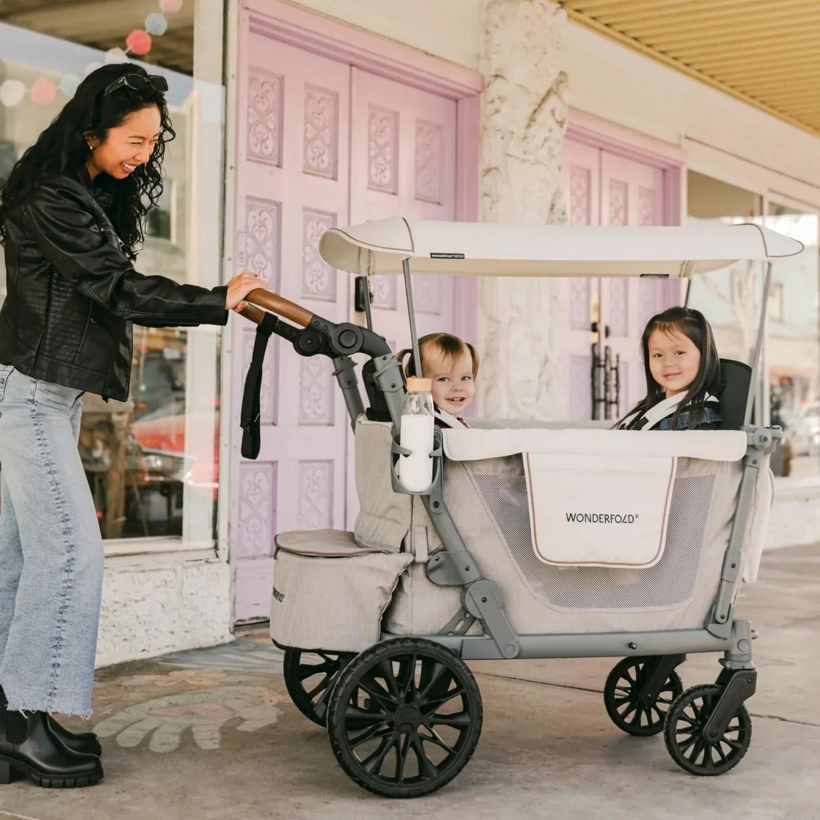 Grey stroller wagon with canopy and two seats; front handle and wheels visible