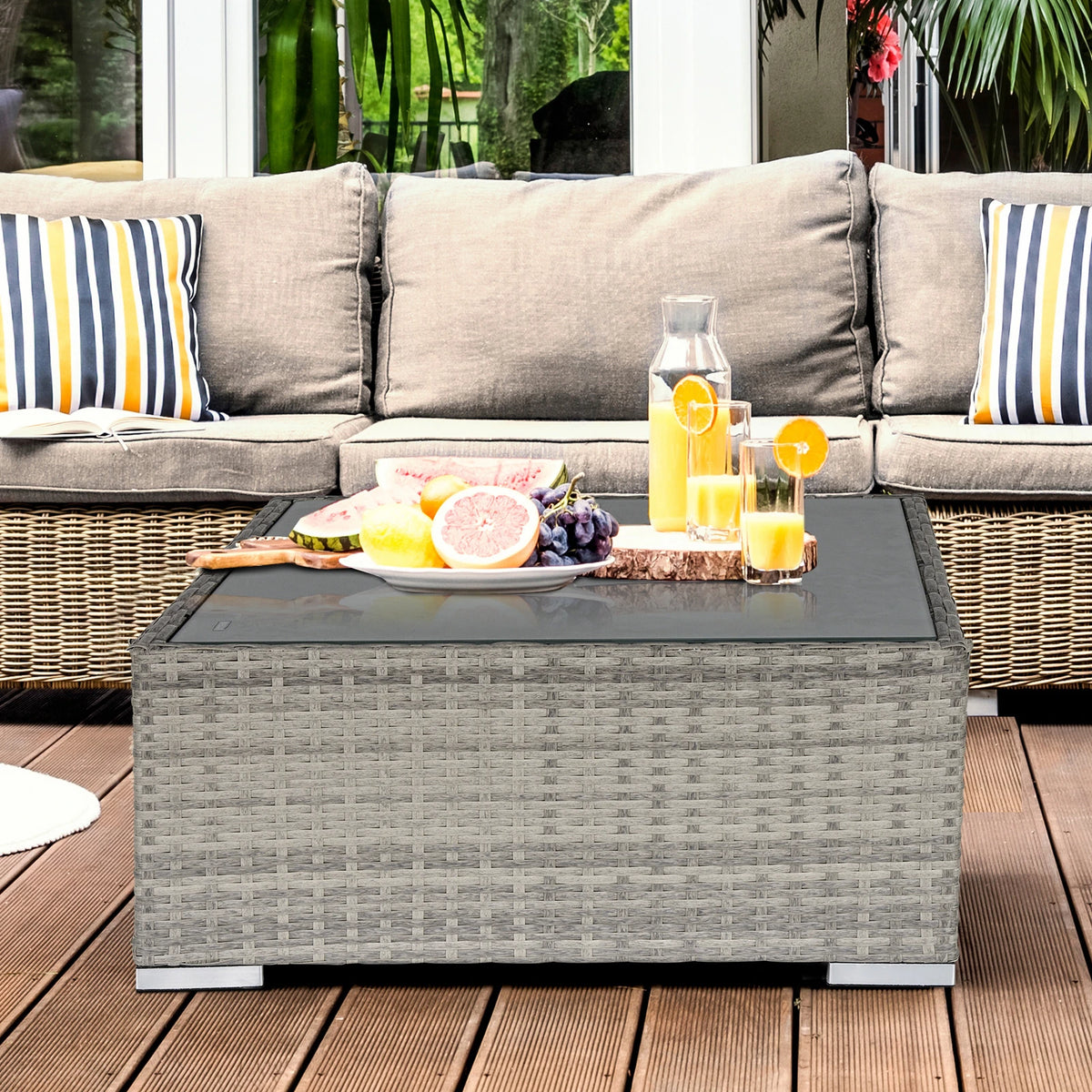 Square gray wicker coffee table with glass top shown beside outdoor seating