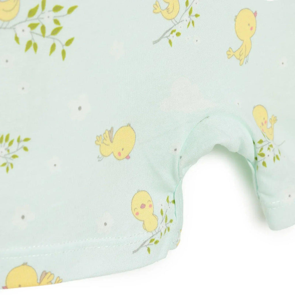 Light blue baby romper leg close-up with yellow chick and green sprig print