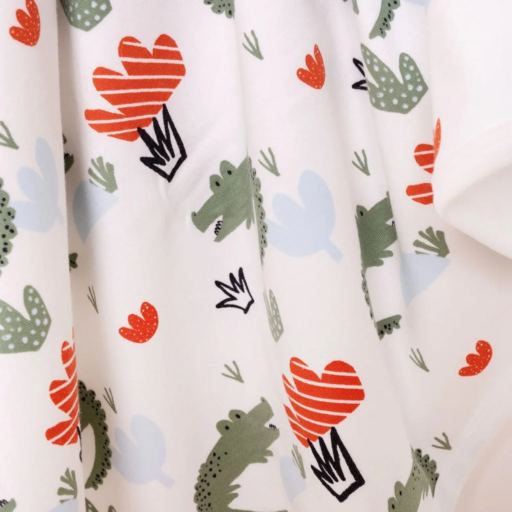 Detail of white kids blanket fabric with cactus figures and red-orange hearts
