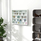 White wall cabinet with glass door showing rows of collectibles inside