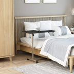 Black C-shaped bedside table with metal legs and caster wheels beside bed