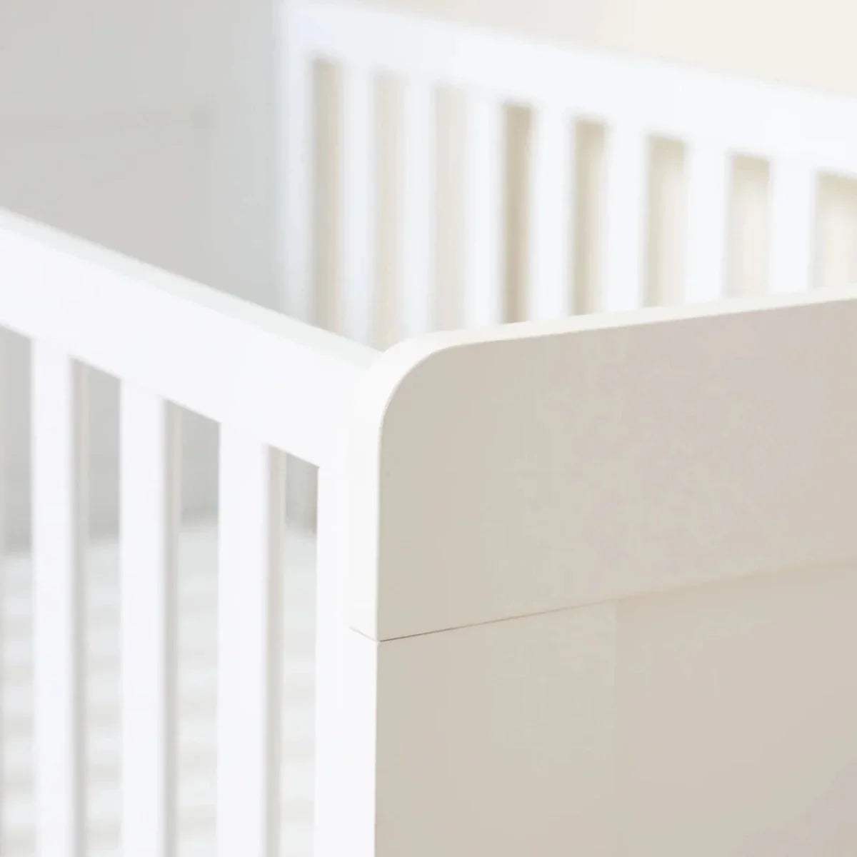 Close-up of white cot bed corner post and vertical safety slats