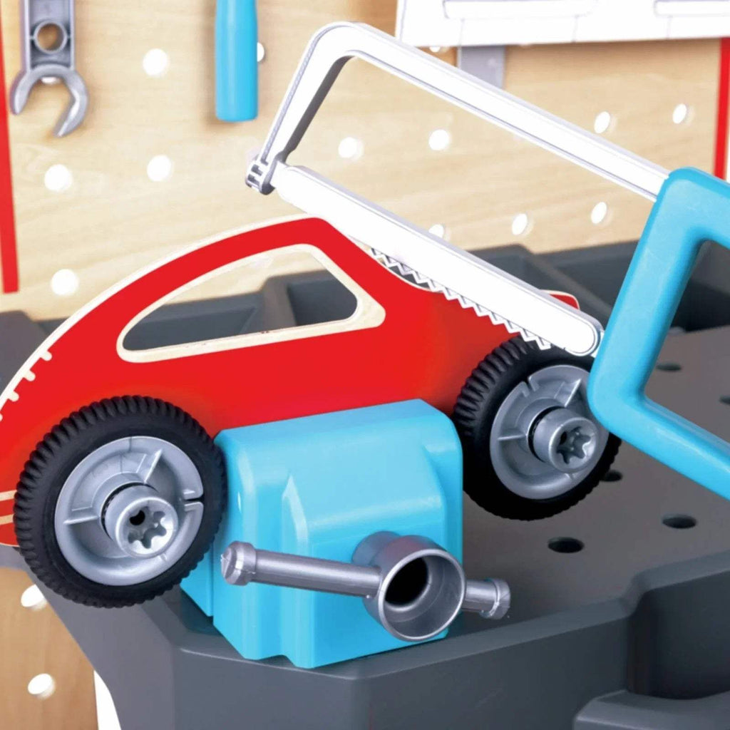 Toy blue car on gray workbench with silver wrench and pegboard background