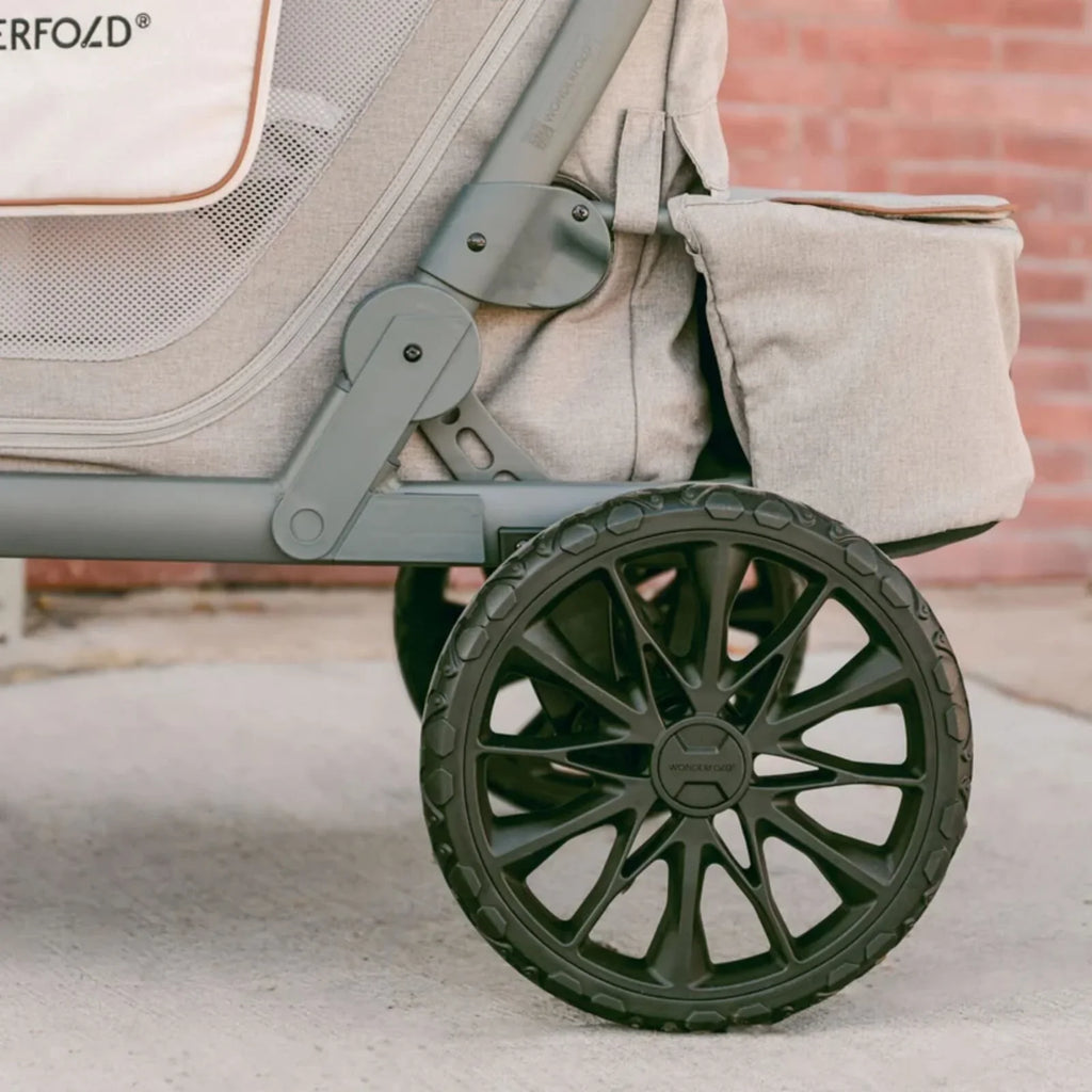 Grey stroller wagon wheel and suspension arm detail with rubber tire tread