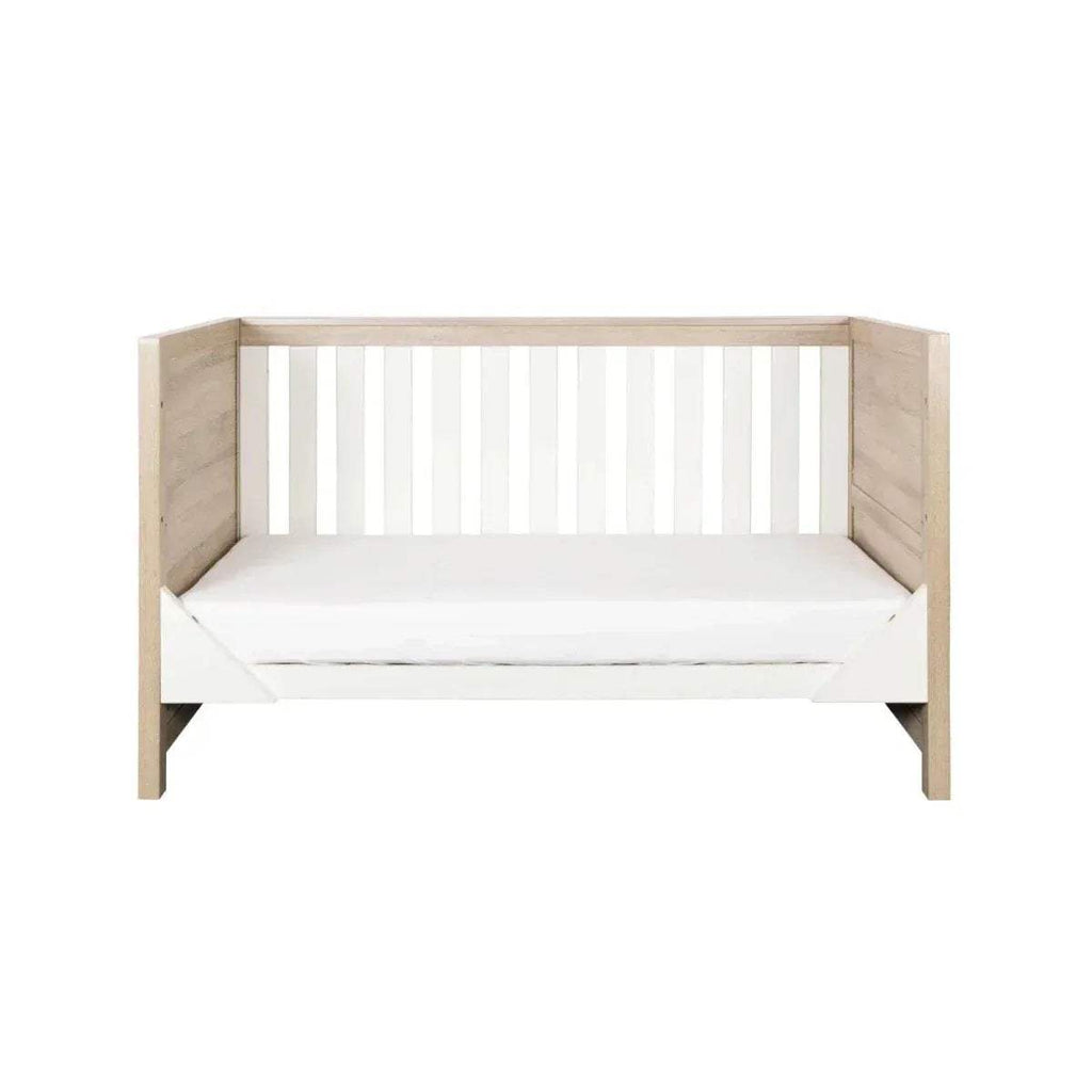 Junior bed with white slatted headboard and light oak side rails, with white mattress