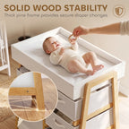 White baby changing table with thick waterproof pad and wooden side handles.
