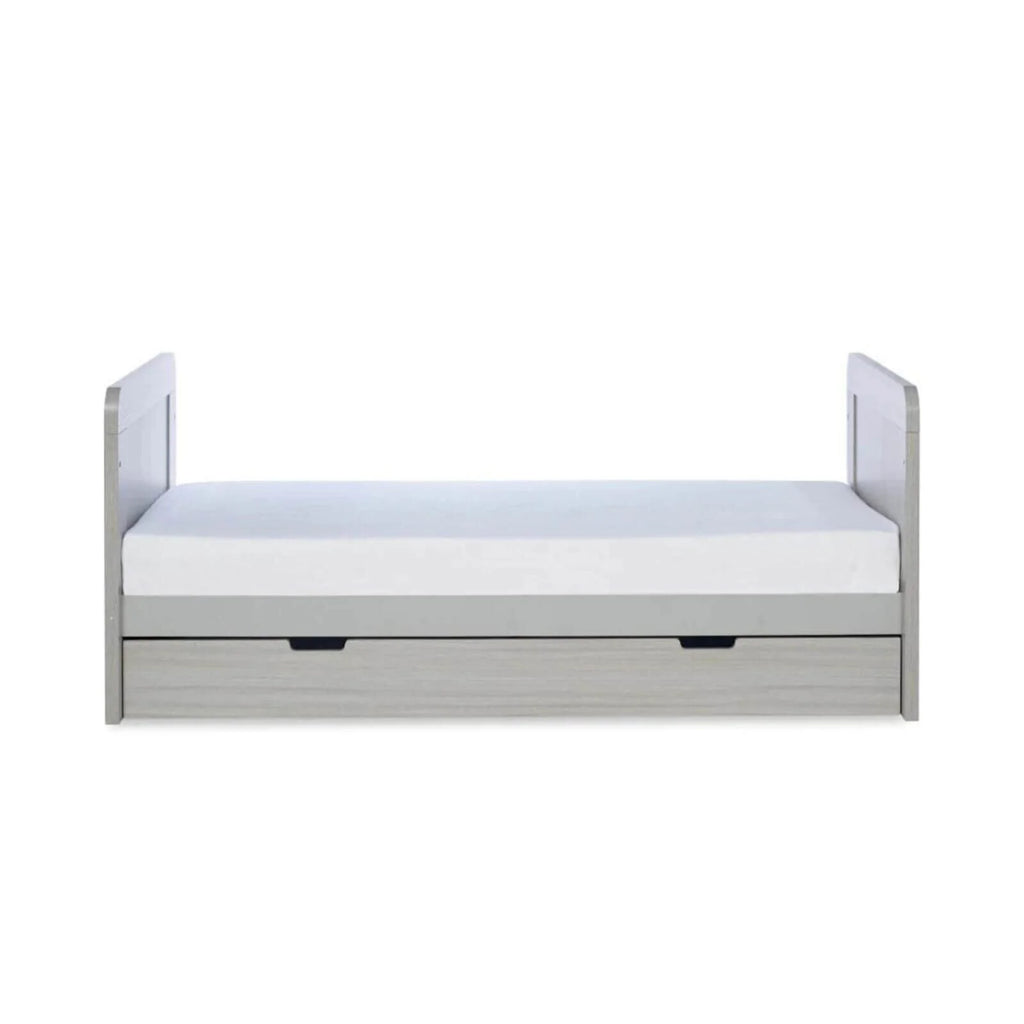 Ash grey cot bed front with white mattress and two drawer handles beneath