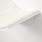 Close-up of cream faux fur cushion on a white curved wall-mounted cat perch shelf