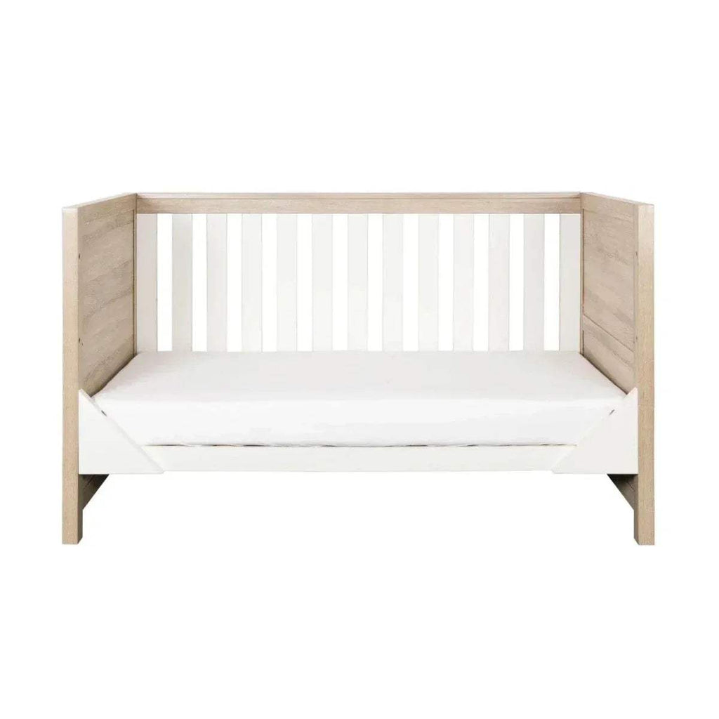 Oak and white wooden cot bed with vertical safety slats and mattress