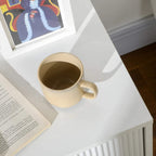 White two-drawer chest top corner with gold-tone ribbed side; mug on the surface