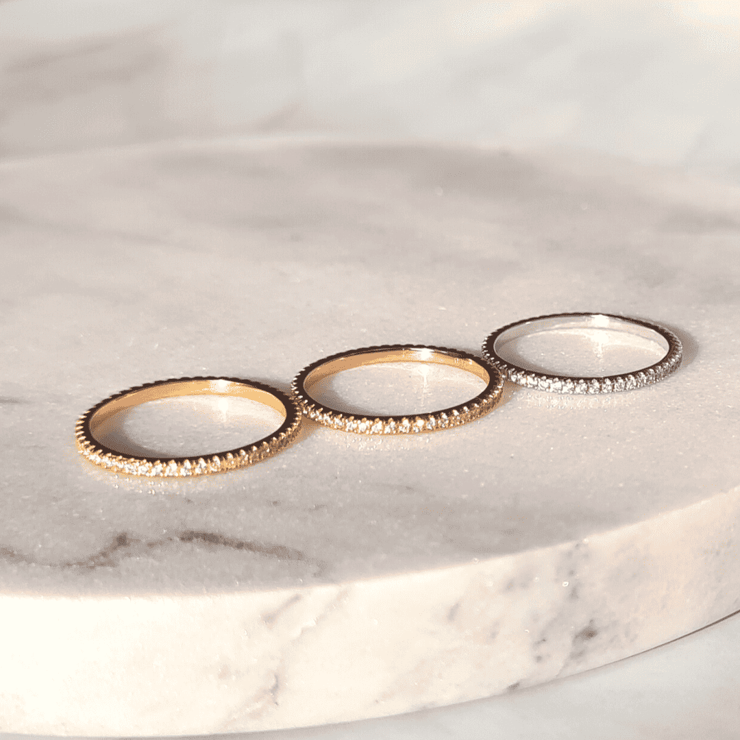 Three thin full eternity rings with pavé stones in gold and silver tones