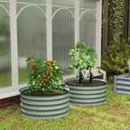 Two green ribbed metal stock tank planters with tomato plants