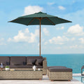 Outdoor patio set with a green umbrella and furniture against a blue sky and ocean background