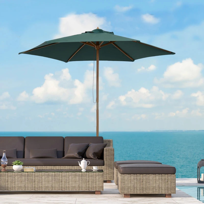 Outdoor patio set with a green umbrella and furniture against a blue sky and ocean background