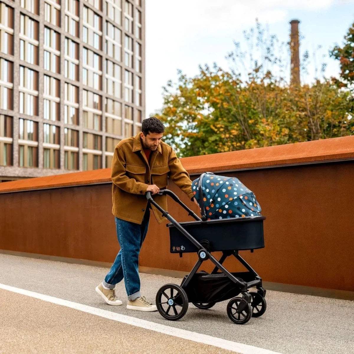Black pushchair with blue polka-dot seat and canopy, four-wheel stroller