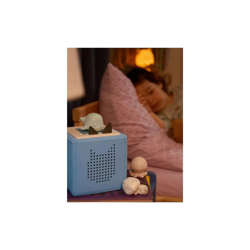 Blue audio player with speaker grill and small whale figure on top beside toys