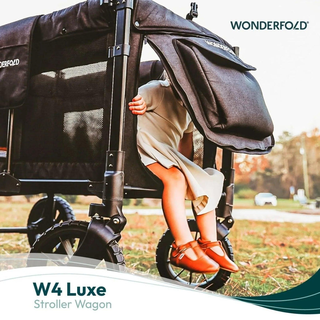 Black stroller wagon with canopy and brown handle, with a child seated inside