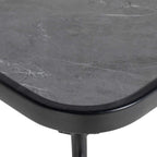Black square tabletop corner with faux-marble texture and curved edge on metal support.